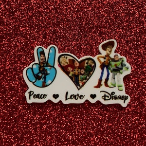 Peut inclure: Autocollant sur le thème de la paix, de l'amour et de Disney avec un signe de paix, un cœur et Woody et Buzz l'Éclair de Toy Story.