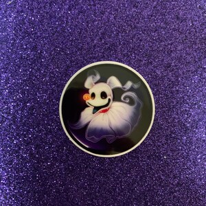 May include: A round sticker with a white background and a black outline. The sticker features a cartoon ghost with a black and purple body and a white face. The ghost has a black bow tie and a small orange nose.