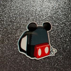 Peut inclure: Un sac à dos noir et rouge avec des oreilles de Mickey Mouse et une poche rouge avec des cercles blancs. Le sac à dos a une sangle blanche et une fermeture éclair blanche.