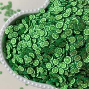 May include: A white heart-shaped bowl filled with green lime slice shaped confetti.
