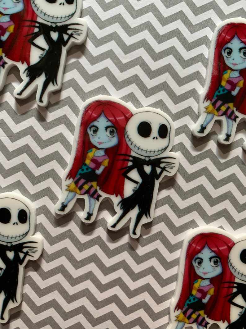 Puede incluir: Dos personajes de dibujos animados, Jack Skellington y Sally de Pesadilla antes de Navidad, se representan en una ilustraci&oacute;n blanca de estilo de dibujos animados. Jack lleva un traje negro y Sally lleva un vestido de retazos. Ambos personajes sonr&iacute;en.