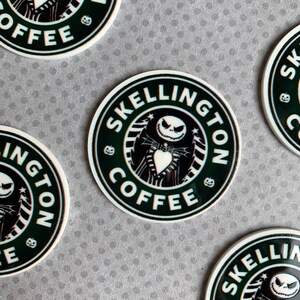 May include: Four black and white round stickers with a green background. The stickers feature a cartoon character with a white face and black eyes. The text on the stickers reads "Skellington Coffee".