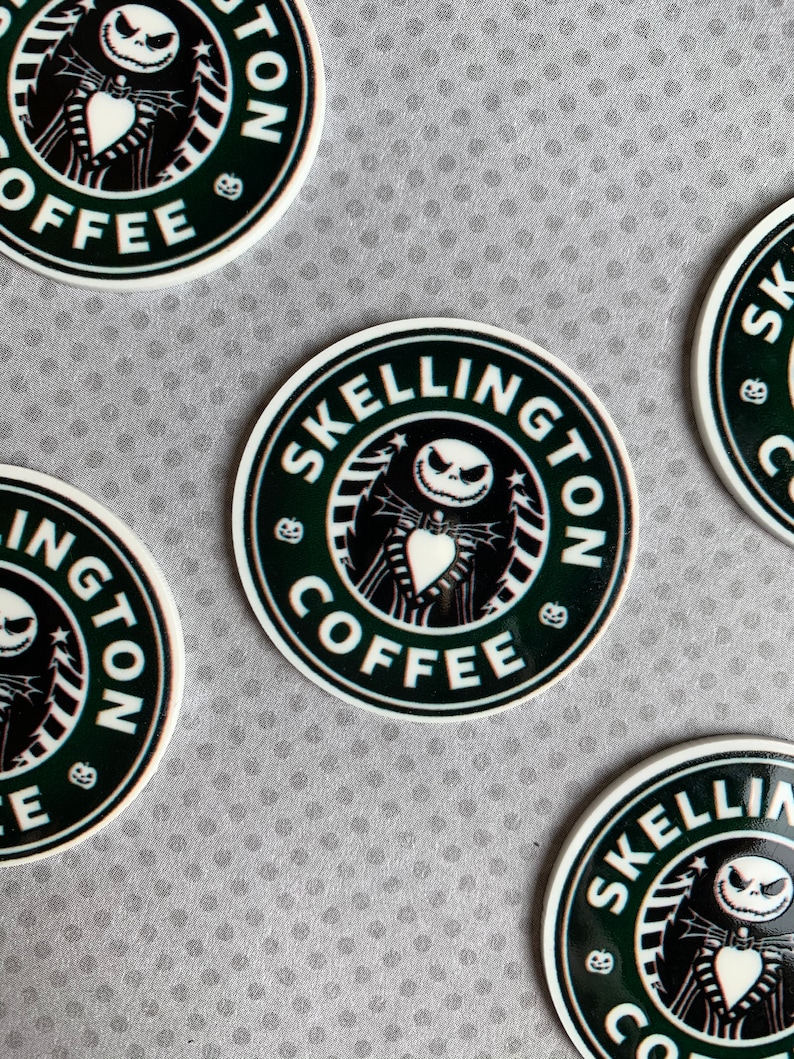 May include: Four black and white round stickers with a green background. The stickers feature a cartoon character with a white face and black eyes. The text on the stickers reads "Skellington Coffee".