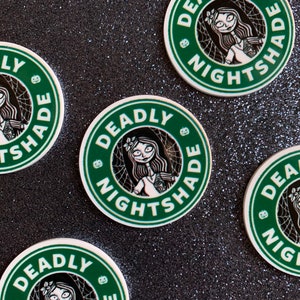 Puede incluir: Cuatro pegatinas redondas verdes y blancas con el texto "Deadly Nightshade" en una fuente estilizada en blanco y negro. Las pegatinas presentan una ilustraci&oacute;n en blanco y negro de una mujer con el pelo largo y un vestido blanco.