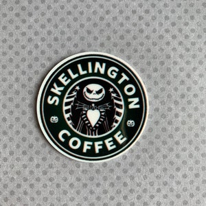 May include: A black and white sticker with a coffee cup design featuring Jack Skellington from the Nightmare Before Christmas movie. The text around the cup reads "Skellington Coffee".