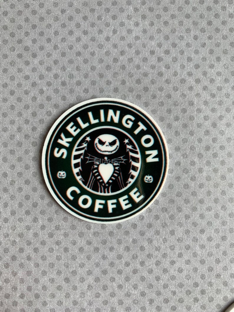 May include: A black and white sticker with a coffee cup design featuring Jack Skellington from the Nightmare Before Christmas movie. The text around the cup reads "Skellington Coffee".