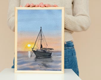 May include: A framed watercolour painting depicting a sailboat on the water at sunset. The sky is a soft blue and orange, and the sun is setting behind the boat. The water is a calm blue and green.