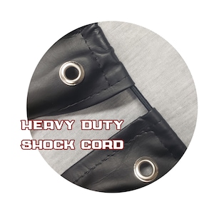 May include: Close-up of a black leather corner with a metal grommet and the text "HEAVY DUTY SHOCK CORD". The leather is stitched and has a reinforced edge. A black shock cord is visible.