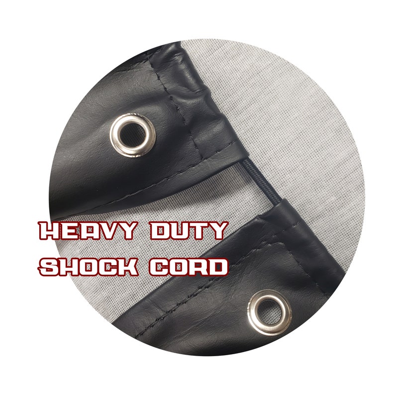 May include: Close-up of a black leather corner with a metal grommet and the text "HEAVY DUTY SHOCK CORD". The leather is stitched and has a reinforced edge. A black shock cord is visible.