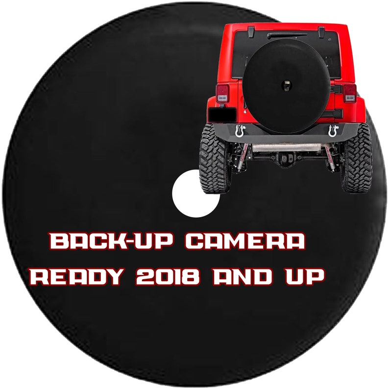 May include: Black spare tire cover with the text "BACK-UP CAMERA READY 2018 AND UP" in red and white. A red Jeep is in the background. The cover has a white circle cut out.