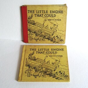 Könnte beinhalten: Zwei Vintage-Exemplare von "The Little Engine That Could" von Watty Piper. Die Bücher haben vergilbte Einbände mit schwarzen Illustrationen einer Lokomotive und Figuren. Das obere Buch hat einen roten Buchrücken. Der Titel ist schwarz gedruckt.