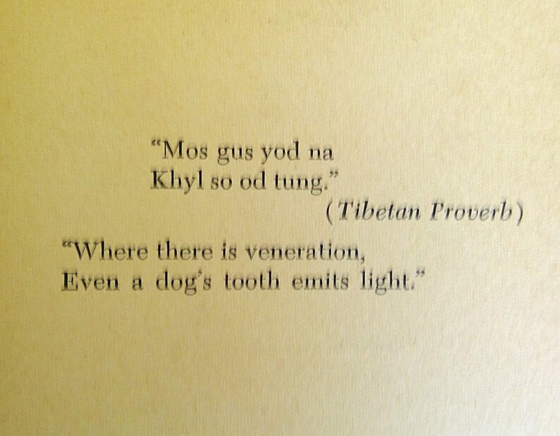 May include: A page from a book with a Tibetan proverb printed in black ink. The quote, in English, reads: "Where there is veneration, Even a dog's tooth emits light."