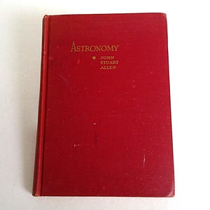 Puede incluir: Un libro rojo de tapa dura titulado "Astronomy" con letras doradas. El nombre del autor, John Stuart Allen, tambi&eacute;n est&aacute; en dorado. El libro est&aacute; cerrado y parece estar en buen estado, con el lomo ligeramente desgastado.