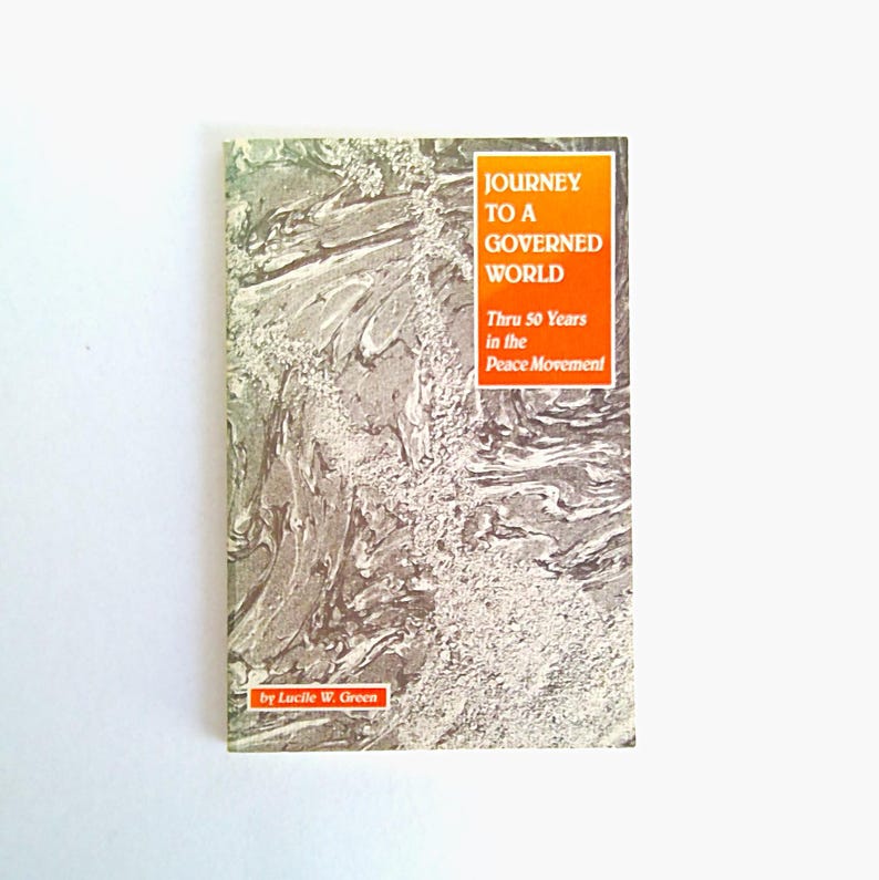 Puede incluir: Un libro titulado "Journey to a Governed World" con el texto "Thru 50 Years in the Peace Movement" y "by Lucile W. Green." La portada tiene un dise&ntilde;o marmolado gris y blanco con un recuadro naranja para el t&iacute;tulo.