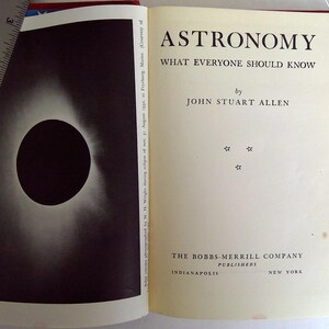 Puede incluir: Libro abierto titulado "Astronom&iacute;a Lo que todos deber&iacute;an saber" por John Stuart Allen. La p&aacute;gina izquierda presenta una imagen en blanco y negro de un eclipse solar. El libro es publicado por The Bobbs-Merrill Company.