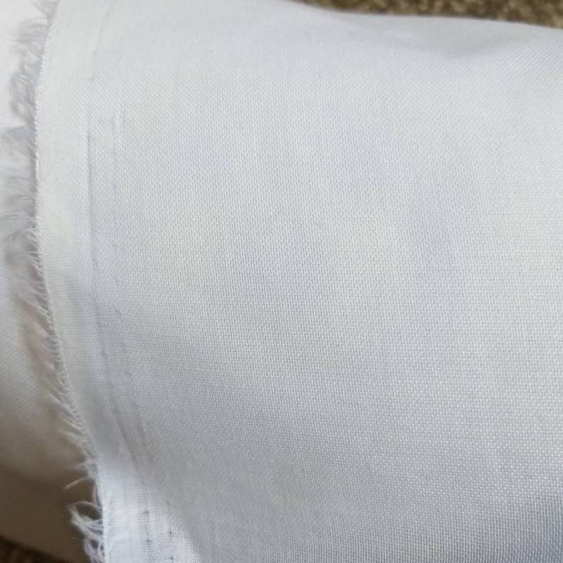 May include: Close-up of a white fabric with a smooth, even texture. The fabric is slightly wrinkled and has a subtle sheen.