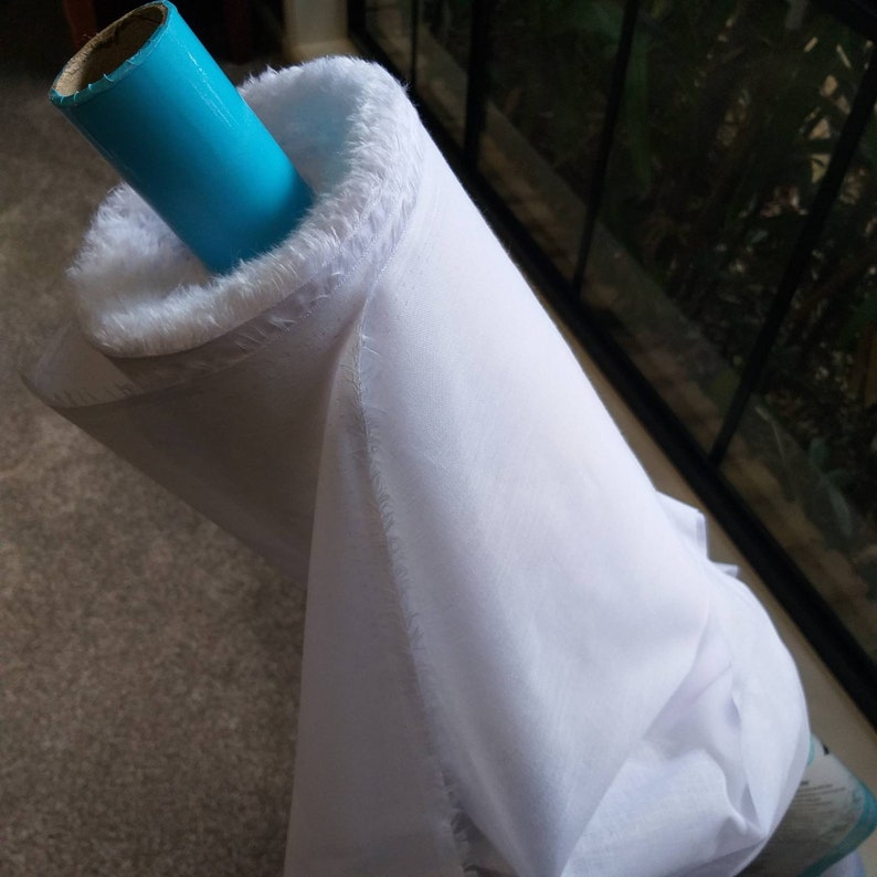 May include: A white fabric roll with a blue cardboard tube. The fabric is rolled up and the tube is sticking out of the roll.
