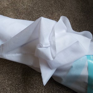 May include: White fabric folded in a bundle. The fabric is smooth and appears to be cotton.