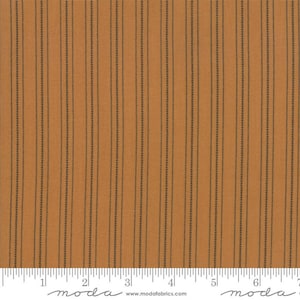 May include: A close-up of a brown fabric with thin black stripes. The fabric has a subtle texture and a slightly distressed look. The fabric is measured in inches with a ruler.