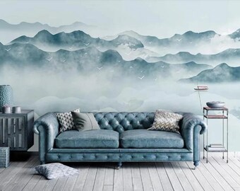 May include: A blue leather sofa with tufted upholstery sits in front of a wall mural depicting a misty mountain range with birds flying overhead.