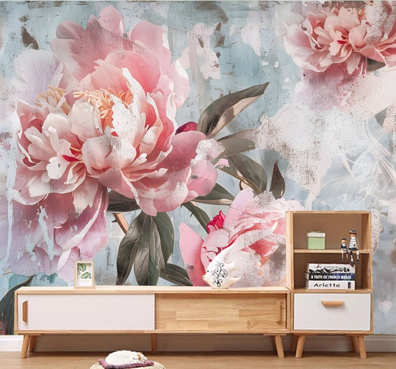 Op de afbeelding: Een bloemenmuurschildering met een verweerde, vintage uitstraling. De muurschildering toont grote roze pioenen met groene bladeren tegen een lichtblauwe achtergrond.