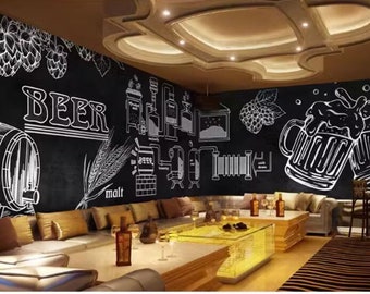 May include: A black and white chalkboard wall mural with a beer brewing theme. The mural features illustrations of hops, malt, beer barrels, and beer mugs. The mural is displayed in a bar or restaurant setting with brown leather couches and a glass coffee table.