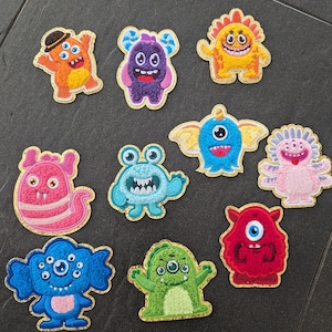 Könnte beinhalten: Zehn bunte Filzmonster-Patches mit goldfarbenem Glitzerbesatz. Jeder Patch zeigt ein anderes Monsterdesign mit einzigartigen Gesichtsausdrücken und Details.