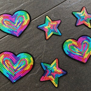 Könnte beinhalten: Sechs bunte Bügelbilder, drei Herzen und drei Sterne, mit einem Regenbogen-Swirl-Design. Die Patches sind aus Pailletten gefertigt und perfekt, um Kleidung, Taschen oder anderen Accessoires einen Hauch von Verspieltheit zu verleihen.