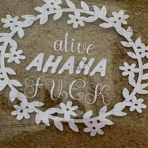 Puede incluir: Pegatina de vinilo blanco con un diseño de corona de flores. El texto dentro de la corona dice "alive AHAHA FUECK".