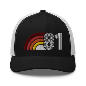 May include: Black trucker hat with a white mesh back. The front features a retro rainbow design and the number "81" in a striped font. The hat is a classic accessory.