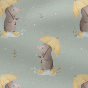 May include: A repeating pattern featuring cartoon moles walking in the rain. Each mole is wearing yellow boots and holding a yellow umbrella. The background is a light green color with small white rain drops and sprigs of grass.