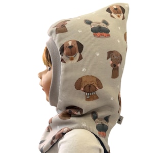 Könnte beinhalten: Hellgraue Babyhaube mit einem sich wiederholenden Muster aus verschiedenen Hundeillustrationen in Braun- und Beigetönen. Die Haube hat eine gerippte Textur und eine graue Einfassung um die Gesichtsöffnung. Pfotenabdrücke sind verstreut.