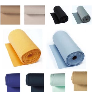 Könnte beinhalten: Verschiedene Stoffrollen in verschiedenen Farben: Beige, Schwarz, Grau, Gelb, Hellblau, Marineblau, Dunkelblau, Mintgrün und Hellbraun. Der Stoff ist gerollt und zeigt die Textur und Farbvariationen.