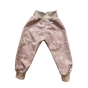 Può includere: Pantaloni da bambino color beige con un motivo ripetuto di animali della foresta e fogliame bianchi. I pantaloni hanno una vita alta beige e polsini abbinati. Il design include orsi, volpi, alberi e ghiande.