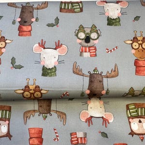 Può includere: Tessuto azzurro con un motivo ripetuto di personaggi di animali natalizi. Le illustrazioni includono renne, topi, koala e giraffe, ognuno adornato con accessori festivi come sciarpe, cappelli e bastoncini di zucchero. Il design ha un tema giocoso e festivo.