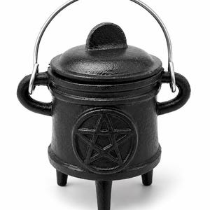 May include: A small, black cast iron cauldron with a lid and a silver handle. The cauldron has three legs and a pentagram design on the front. This decorative cauldron is perfect for Halloween or other mystical themes.