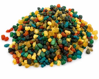 May include: A pile of colorful resin granules in shades of red, orange, yellow, green, and blue. The granules have a textured appearance and are scattered against a white background. The image showcases a variety of colors and textures.