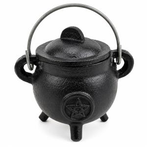 May include: A small, black cast iron cauldron with a lid and a metal handle. The cauldron has three legs and a pentagram symbol on the front. The cauldron is designed for decorative or ritualistic purposes.