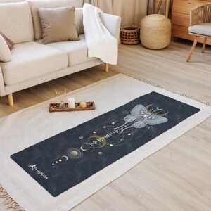 Pode incluir: Um tapete de ioga azul escuro com um desenho de mariposa celestial em azul claro e dourado. O tapete apresenta um padr&atilde;o geom&eacute;trico com luas e estrelas, e o texto "Comfy Yoga" &eacute; vis&iacute;vel em branco.