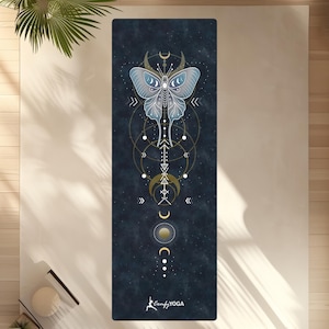 Pode incluir: Um tapete de ioga retangular com fundo azul escuro e um desenho de borboleta celestial. A borboleta &eacute; azul claro com detalhes dourados, e o tapete apresenta formas geom&eacute;tricas e o texto "Comfy YOGA".