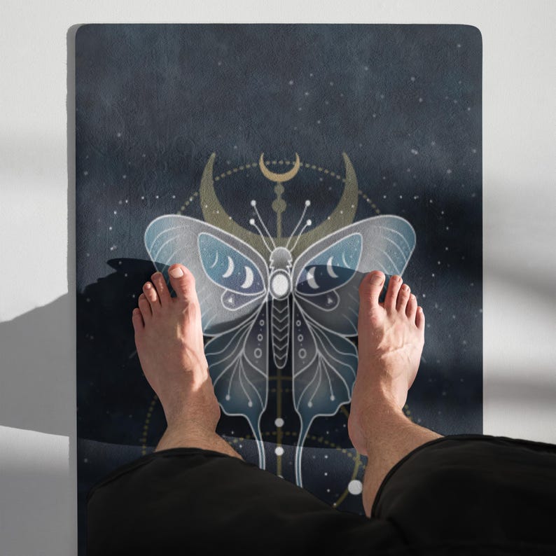 Pode incluir: Um tapete de ioga azul escuro com um design de borboleta celestial e detalhes de lua crescente. A borboleta tem asas azuis claras e um corpo branco. O tapete &eacute; retangular e tem uma superf&iacute;cie texturizada.