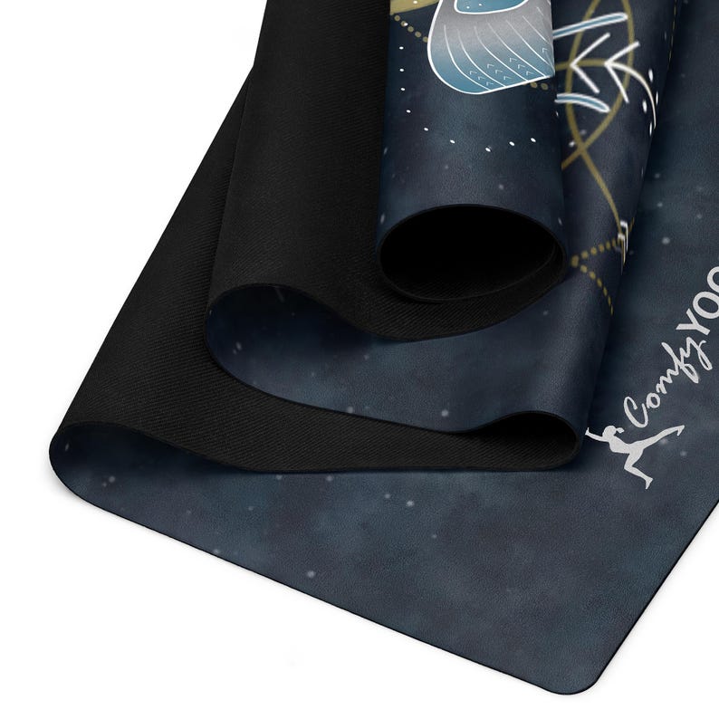 Pode incluir: Um tapete de ioga enrolado com um design de noite estrelada azul escuro. O tapete apresenta um gr&aacute;fico branco de uma pessoa em uma pose de ioga e as palavras "Comfy Yoga". O tapete &eacute; feito de um material macio e flex&iacute;vel.