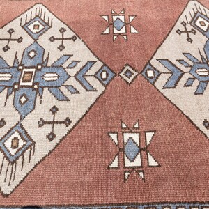May include: A close-up of a red and white patterned rug with a geometric design. The rug has a traditional, tribal feel and features blue and brown accents.