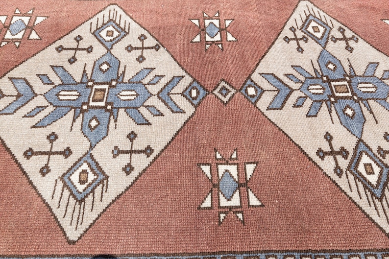 May include: A close-up of a red and white patterned rug with a geometric design. The rug has a traditional, tribal feel and features blue and brown accents.