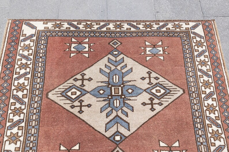 May include: A red, white, and blue patterned rug with a geometric design. The rug has a border with a repeating pattern of stars and diamonds.