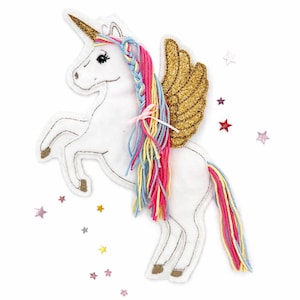 Könnte beinhalten: Ein weißes Filz-Einhorn mit goldenem Horn und Flügeln. Das Einhorn hat eine mehrfarbige Mähne und einen Schweif mit rosa, blauen und gelben Strähnen. Kleine sternförmige Verzierungen umgeben das Einhorn.