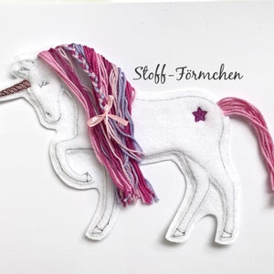 Könnte beinhalten: Weißes Filz-Einhorn mit rosa und lila Garnmähne und -schwanz. Das Einhorn hat einen rosa Stern auf dem Rücken und der Text "Stoff-Förmchen" steht darüber.
