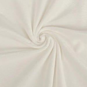 Könnte beinhalten: Nahaufnahme eines cremefarbenen, plüschigen Stoffes mit weicher, samtiger Textur. Der Stoff ist in einem Spiralmuster angeordnet, wodurch ein Gefühl von Tiefe und Bewegung entsteht. Das Material scheint eine weiche Decke oder ein Überwurf zu sein.