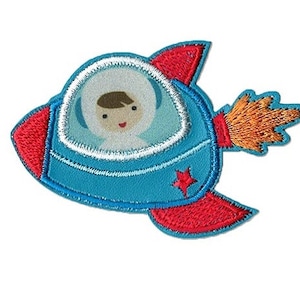 Könnte beinhalten: Eine blaue und rote Rakete mit einem weißen Fenster und einem Cartoon-Astronauten im Inneren. Die Rakete hat eine Flamme, die aus dem Heck kommt.