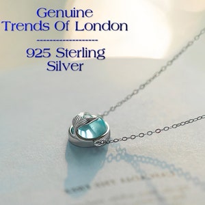 Op de afbeelding: Een zilveren ketting met een blauwe edelsteen hanger met een zeemeerminstaart ontwerp. De ketting is gelabeld "Genuine Trends Of London 925 Sterling Silver."